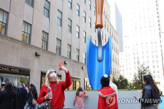 올든버그의 마지막 작품 '모종삽' NEW YORK, NEW YORK - MARCH 22: People walk past the "Plantoir, Blue" sculpture iat the Channel Gardens in Rockefeller Center on March 22, 2022 in New York City. A sculpture titled "Plantoir, Blue" by artists Claes Oldenburg And Coosje Van Bruggen officially opened to the public to