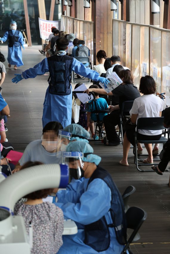 7만3천582명의 코로나19 신규 확진자가 발생, 83일 만에 최다를 기록한 19일 서울 송파구 보건소 선별진료소에서 시민들이 검사를 기다리고 있다.