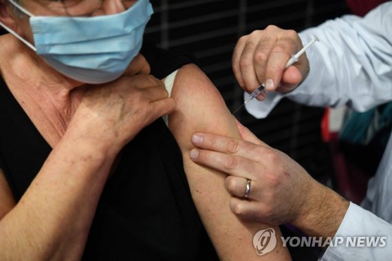 프랑스 시민의 코로나19 백신 접종 모습 (FILES) In this file photo taken on March 02, 2021 an elderly woman receives a dose of the Pfizer-BioNtech Covid-19 vaccine, at a vaccination centre in Garlan, western France. - The EU's health and medicine agencies said on July 11, 2022 they were recommending a second booster