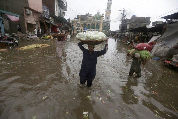 [AP/뉴시스] 21일 파키스탄 펀자브 라호르에서 장마비에 시장에 홍수가 나자 농부들이 농산물을 들고 피하고 있다