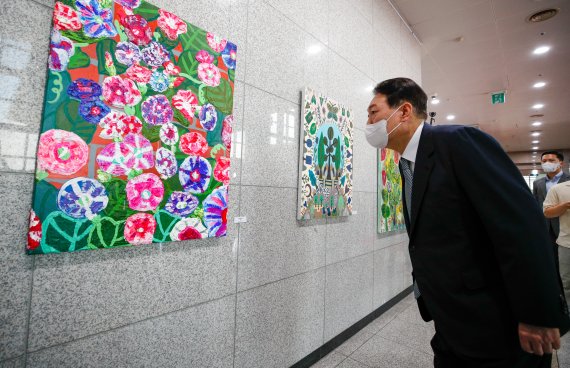 윤석열 대통령이 25일 오전 용산 대통령실에서 출근길 약식 기자회견(도어스테핑)을 마친 뒤 그림을 둘러보고 있다. 이날 대통령실 1층 양옆 벽면에는 발달장애 작가들의 작품 15점이 처음 전시됐다. 대통령실사진기자단 2022.7.25/뉴스1 © News1 안은나 기자