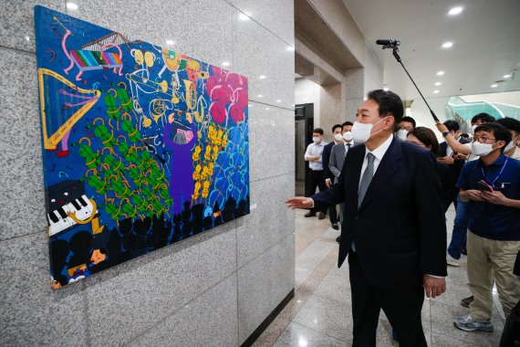 윤석열 대통령이 25일 오전 용산 대통령실에서 출근길 약식 기자회견(도어스테핑)을 마친 뒤 그림을 둘러보고 있다. 이날 대통령실 1층 양옆 벽면에는 발달장애 작가들의 작품 15점이 처음 전시됐다. 대통령실사진기자단 2022.7.25/뉴스1 © News1 안은나 기자