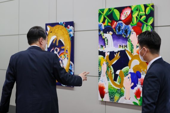 윤석열 대통령이 25일 오전 용산 대통령실에서 출근길 약식 기자회견(도어스테핑)을 마친 뒤 로비에 걸린 그림을 둘러보고 있다. 이날 대통령실 1층 양옆 벽면에는 발달장애 작가들의 작품 15점이 처음 전시됐다. 대통령실사진기자단 2022.7.25/뉴스1 © News1 안은나 기자