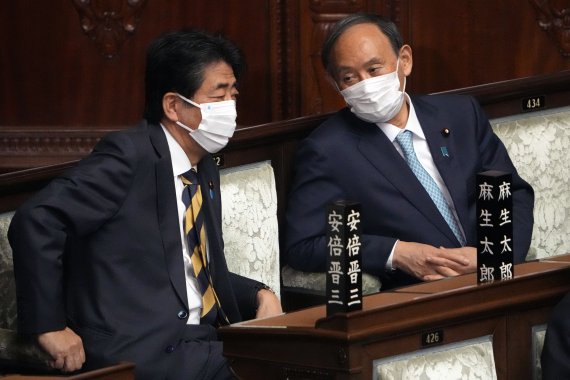 [도쿄(일본)=AP/뉴시스]지난 1월 27일 일본 국회에서 아베 신조 전 총리(왼쪽)와 스가 요시히데 전 총리가 중의원에서 기시다 후미오 총리의 연설을 들으며 이야기 하고 있다. 2022.07.25.