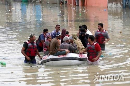 폭우로 고립된 카라치 주민이 구조대와 함께 보트로 이동하는 모습. [신화 연합뉴스 자료사진. 재판매 및 DB 금지]