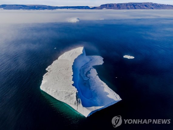 바다에 홀로 떠 있는 빙하 A melting pond is seen inside an iceberg from the Greenland ice sheet in the Baffin Bay near Pituffik, Greenland on July 17, 2022 as captured on a NASA Gulfstream V plane while on an airborne mission to measure melting Arctic sea ice. - New observations from ICESAT-2 show remarkable A