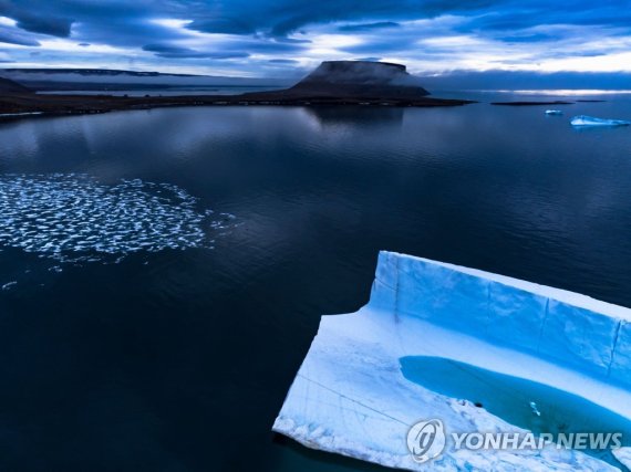 그린란드 해상에 떠 있는 빙하 A melting pond is seen inside an iceberg from the Greenland ice sheet in the Baffin Bay near Pituffik, Greenland on July 20, 2022 as captured on a NASA Gulfstream V plane while on an airborne mission to measure melting Arctic sea ice. - New observations from ICESAT-2 show remarkable