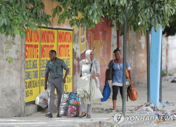 27일(현지시간) 총격 피해서 대피하는 아이티 포르토프랭스 주민들 Residents flee the area after gangs waged intense gun battles, shuttering main avenues and a municipal market in the downtown area of the capital, in Port-au-Prince, Haiti July 27, 2022. REUTERS/Ralph Tedy Erol