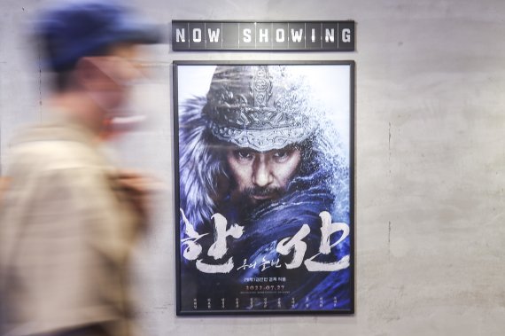 지난달 31일 오전 서울시내 영화관을 찾은 시민이 '한산'광고판을 지나가고 있다. 뉴시스