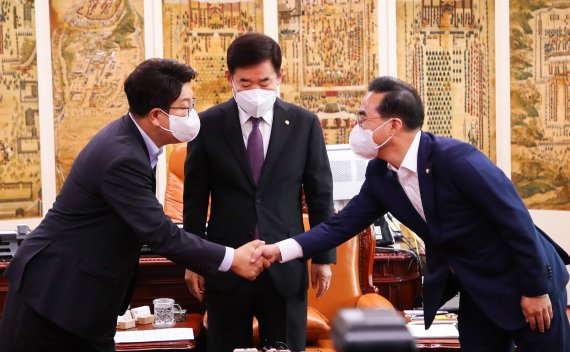 권성동 국민의힘 전 원내대표(왼쪽)와 박홍근 더불어민주당 원내대표가 국회에서 열린 회동에서 악수하고 있다. 가운데는 김진표 국회의장. 공동취재, 뉴스1.