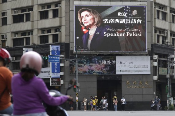 People walk past a billboard welcoming U.S. House Speaker Nancy Pelosi, in Taipei, Taiwan, Wednesday, Aug 3, 2022. Pelosi arrived in Taiwan late Tuesday, becoming the highest-ranking American official in 25 years to visit the self-ruled island claimed by China, which quickly announced that it would 