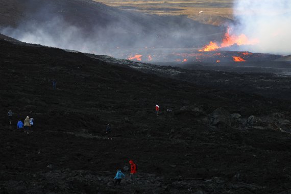 [레이캬비크=AP/뉴시스] 3일(현지시간) 아이슬란드 수도 레이캬비크 남서쪽 32㎞ 떨어진 파그라달스퍄들 화산 부근에서 사람들이 흘러내리는 용암을 구경하고 있다. 현지 당국은 이 화산이 활동을 멈춘 지 8개월 만에 활동을 재개했다고 밝혔다. 2022.08.04.