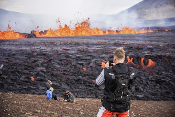 [레이캬비크=AP/뉴시스] 3일(현지시간) 아이슬란드 수도 레이캬비크 남서쪽 32㎞ 떨어진 파그라달스퍄들 화산 부근에서 사람들이 흘러내리는 용암을 구경하고 있다. 현지 당국은 이 화산이 활동을 멈춘 지 8개월 만에 활동을 재개했다고 밝혔다. 2022.08.04.