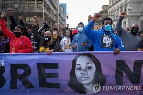 브레오나 테일러의 죽음에 항의하는 시위대 (FILES) In this file photo taken on March 13, 2021 Protestors carry a banner with the face of Breonna Taylor during a rally in remembrance on the one year anniversary of her death in Louisville, Kentucky. - The US Justice Department announced on Agust 4, 2022 that it was charg