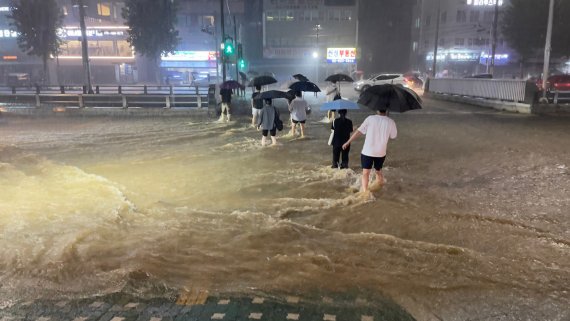 중부지방을 중심으로 폭우가 쏟아진 8일 밤 서울 관악구 도림천이 범람, 주변을 지나는 시민들이 아슬아슬하게 발걸음을 재촉하고 있다.