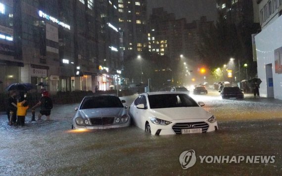 지난 8일 밤 서울 강남구 대치동 은마아파트 부근 도로와 인도가 물에 잠기면서 차량과 보행자가 통행하는 데 불편을 겪고 있다. /연합뉴스