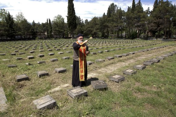 [트빌리시( 미 조지아주) = AP/뉴시스] 미 조지아주의 군 묘지에서 올 해 5월9일 조지아 정교회 사제가 전몰용사들의 무덤에 축원하고 있다. 인근 요나산에서는 산악훈련 중 기후변화와 관련된 사상자가 발생했다.