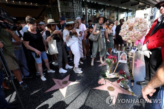 뉴턴 존을 추모하며 모인 사람들 People stop by the star of late actor Olivia Newton-John which is adorned with flowers and photographs on the Hollywood Walk of Fame in Los Angeles, California, U.S., August 8, 2022. REUTERS/Mario Anzuoni
