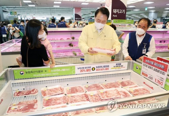 물가동향 점검에 나선 윤석열 대통령이 11일 서울 서초구 양재동 하나로마트 양재점에서 한 시민과 삼겹살을 살펴보고 있다.