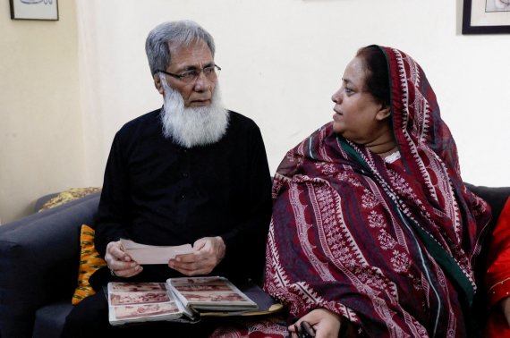 알리 하반 바카이가 파키스탄 카라치에 있는 자택에서 아내와 얘기를 나누면서 가족 사진을 보고 있다. ⓒ 로이터=뉴스1