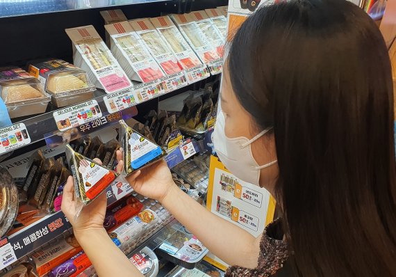 이마트24 매장을 찾은 고객이 '더빅삼각김밥'을 살펴보고 있다. /이마트24 제공
