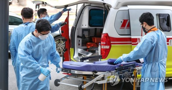 서울 광진구 혜민병원에서 코로나19 환자를 옮겼던 침대를 소독하고 있는 구급대원들. /연합뉴스