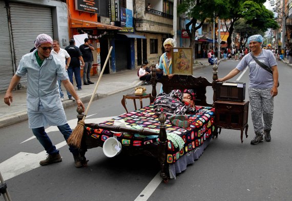 콜롬비아 이타구이에서 주민들이 '세계 게으름의 날'을 기념해 한 여성이 누워 있는 침대를 끌며 거리를 행진하고 있다. AFP연합뉴스