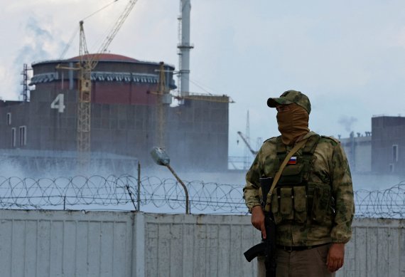 Um soldado em uniforme militar com a bandeira russa guarda a usina nuclear de Zaporizhia, na Ucrânia, no quarto dia.  ⓒ Reuters = Notícias 1 ⓒ Repórter do News1 Min Kyung Kang