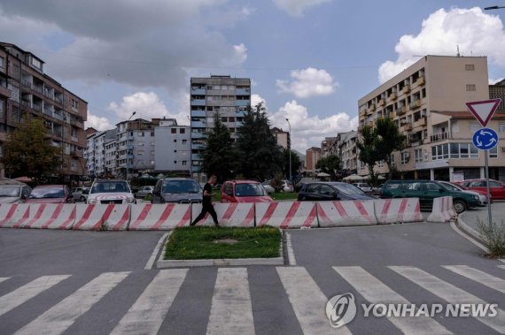 코소보 북부의 세르비아계 밀집지역인 미트로비차 A man walks near the Ibar River bridge in the town of Mitrovica, on August 26, 2022. - Tensions between Serbia and Kosovo soared late last month when Kosovo's government declared that Serb-issued identity documents and vehicle license plates would no longer be valid in Koso