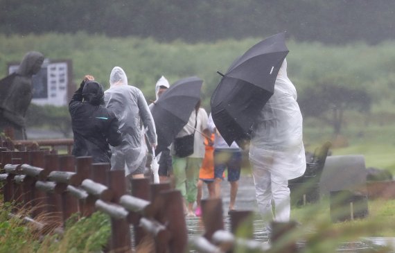 [서귀포=뉴시스] 우장호 기자 = 제11호 태풍 '힌남노' 간접영향으로 비바람이 부는 2일 오후 제주 서귀포시 대정읍 송악산에 우산을 쓴 관광객들이 걸어가고 있다. 기상청은 태풍 힌남노가 이날 우리나라를 향해 방향을 틀어 오는 6일 새벽께 서귀포 남동쪽 해상까지 접근할 것으로 예측했다. 2022.09.02. woo1223@newsis.com