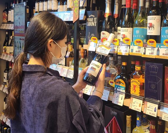 한 고객이 이마트24 매장에서 '꼬모 리슬링' 와인 상품을 살펴보고 있다. 이마트24 제공.