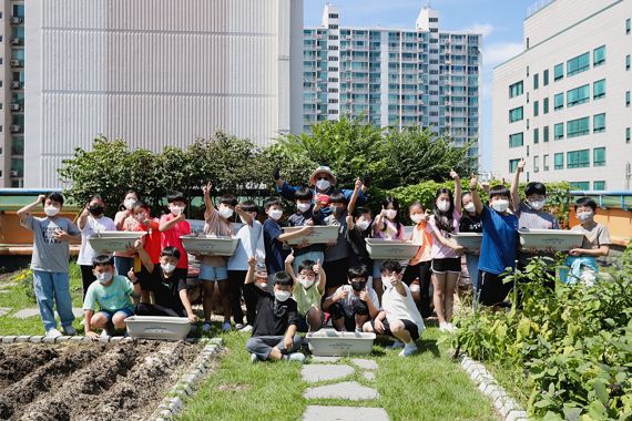 교장선생님과 학생들이 지난 1일 서울시 동작구 소재 보라매초등학교에서 화분에 씨앗을 심는 체험 활동을 마치고 기념촬영을 하고 있다. 우리금융그룹 제공