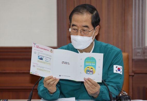 한덕수 국무총리가 7일 정부서울청사에서 열린 코로나19 대응 중앙재난안전대책본부 회의를 시작하기에 앞서 추석에 귀성객들에게 나누어 줄 '일상방역 수칙, 의료이용 안내' 팸플릿을 보고 있다. 연합