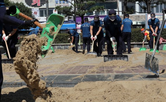 [부산=뉴시스] 하경민 기자 = 제11호 태풍 '힌남노'의 영향으로 부산 곳곳에서 피해가 발생한 가운데 7일 오전 서구 송도해수욕장 해변에서 경찰관들이 해일로 인해 인도를 뒤덮은 모래를 치우고 있다. 2022.09.07. yulnetphoto@newsis.com