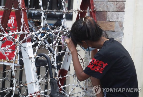 미얀마 인세인교도소 앞에서 가족을 기다리는 여성 epa09530244 A woman lean on the barricade as she waits for the released of her family member outside the Insein prison in Yangon, Myanmar, 18 October 2021. Myanmar's junta chief Min Aung Haling announced the released of over 5,000 people who were participated in the anti-c