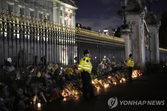 시민들이 놓은 조화가 쌓은 버킹엄 궁 Policemen stand outside Buckingham Palace in London, Friday, Sept. 9, 2022, after the death of Britain's Queen Elizabeth II was announced. Queen Elizabeth II, Britain's longest-reigning monarch and a rock of stability across much of a turbulent century, died Thursday after 70 ye