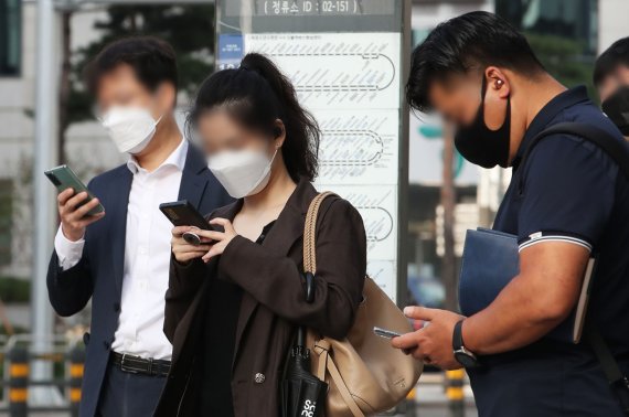 5일 오전 서울 시내 한 버스정류장에서 시민들이 스마트폰을 하고 있다. 뉴시스.