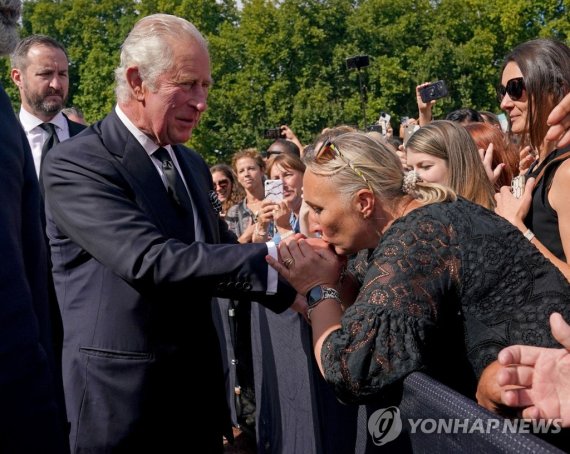 찰스3세 국왕 손등에 입맞춤하는 시민 A well-wisher kisses the hand of King Charles III during a walkabout outside Buckingham Palace, London, to view messages and tributes following the death of Queen Elizabeth II on Thursday. Picture date: Friday September 9, 2022. Yui Mok/Pool via REUTERS