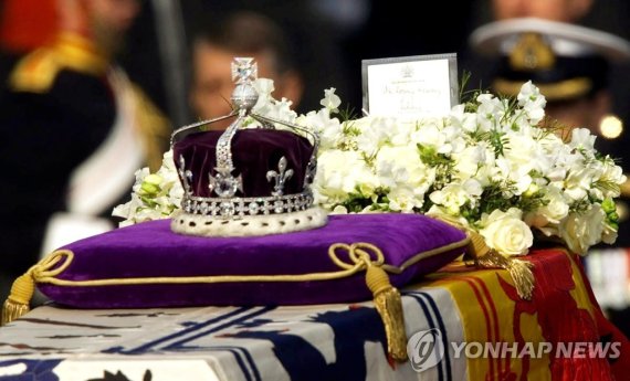 2002년 엘리자베스 1세의 관 위에 놓였던 왕관 FILE - The Koh-i-noor, or "mountain of light," diamond, set in the Maltese Cross at the front of the crown made for Britain's late Queen Mother Elizabeth, is seen on her coffin, along with her personal standard, a wreath and a note from her daughter, Queen Elizabeth II, a