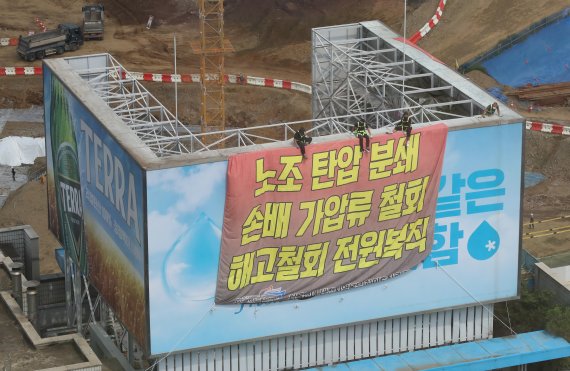 하이트진로 본사 옥상에서 고공농성을 하고 있는 민주노총 공공운수노조 화물연대 조합원들이 지난 8월 18일 오후 서울 강남구 하이트진로 본사 앞에서 열린 '고공농성 투쟁 승리 결의대회'를 지켜보고 있다. /사진=뉴시스