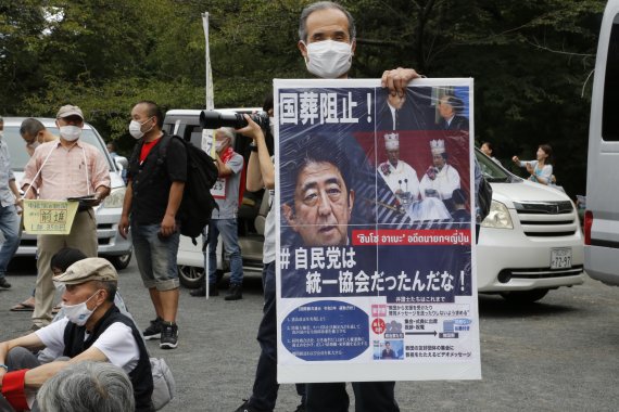 23일 일본 도쿄의 한 공원에서 한 남성이 아베 신조 전 일본 총리의 국장에 반대하는 포스터를 들고 시위에 참여하고 있다 사진=뉴시스화상