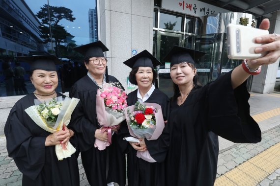 26일 오전 대구시교육청 행복관에서 '대구내일학교(성인 문해교육 프로그램) 초등 제10회·중등 제7회 졸업식'이 열렸다. 꽃다발을 든 졸업생들이 교육청 마당에서 마스크를 벗고 활짝 웃으며 기념 촬영을 하고 있다. /뉴스1