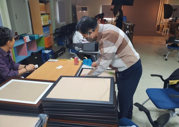 사진 현상과 액자 제작 작업 중인 인클로버재단 관계자들 [촬영 이상서]