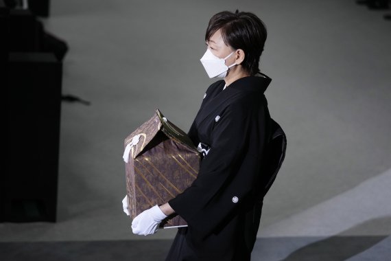 아베 신조 전 일본 총리의 부인인 아베 아키에 여사가 27일 고인의 유골을 들고 국장이 열리는 도쿄의 닛폰부도칸에 들어서고 있다. /AP 뉴시스