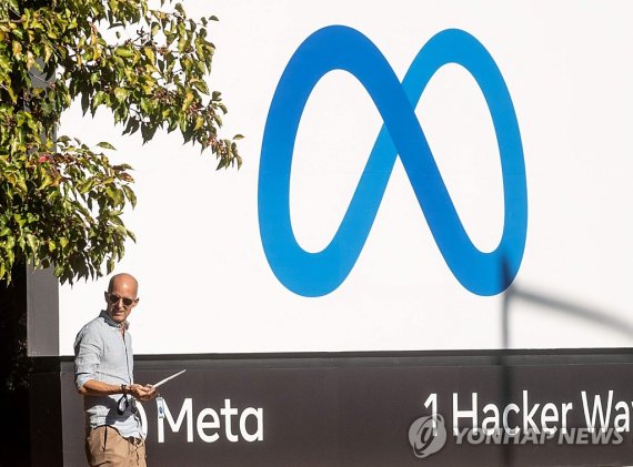 (FILES) In this file photo taken on October 28, 2021, man passes a newly unveiled logo for "Meta", the new name for Facebook's parent company, outside Facebook headquarters in Menlo Park. - Meta said on September 27, 2022, it derailed a campaign out of China to influence upcoming US elections by pos