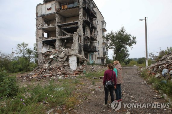 15일(현지시간) 파괴된 주거용 건물 옆에 서 있는 이지움 주민 Women stand near a residential building destroyed by a military strike in the town of Izium recently liberated by the Ukrainian Armed Forces during a counteroffensive operation, amid Russia's attack on Ukraine, in Kharkiv region, Ukraine September 15, 2022. REUTER