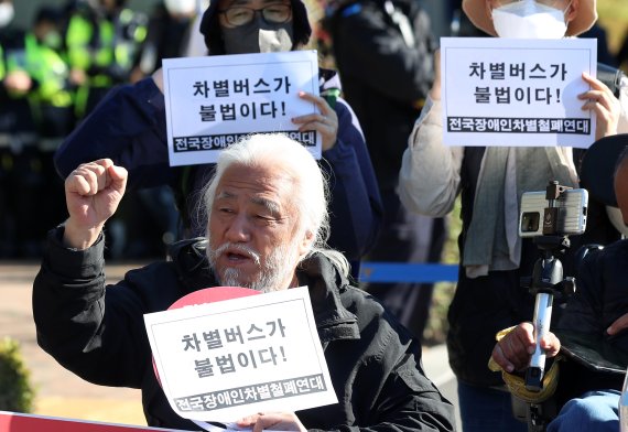 [서울=뉴시스] 이영환 기자 = 박경석 전국장애인차별철폐연대(전장연) 대표가 18일 오전 서울 서초구 서울중앙지방법원 앞에서 버스운행 방해 혐의 재판 선고에 앞서 기자회견을 열고 구호를 외치고 있다. 박 대표는 지난 2021년 4월 8일 마로니에 공원 버스정류장 앞에서 160번 노선버스가 정류장에 정차하자 승차를 요구하였고, 버스기사는 "휠체어를 탄 장애인은 버스를 탈 수 없다"며 탑승을 거부했다. 이 과정에서 박 대표는 15분간 왜 이 버스를 탈 수 없는가에 대한 발언을 하였고 이에 검찰은 신고하지 않은 집회를 개최해 위력으로 버