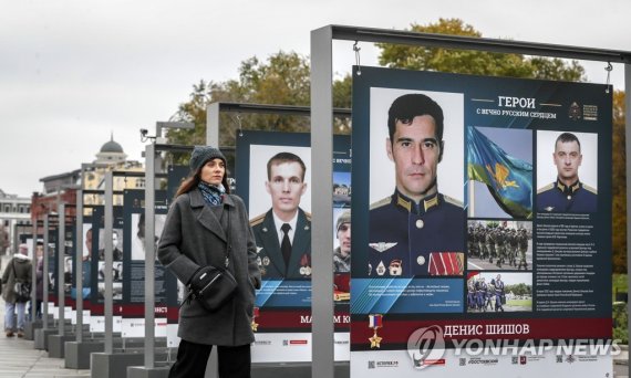 19일 한 여성이 모스크바에서 버스 정류장 인근에 세워진 군사 홍보물 옆을 지나고 있다. 연합뉴스