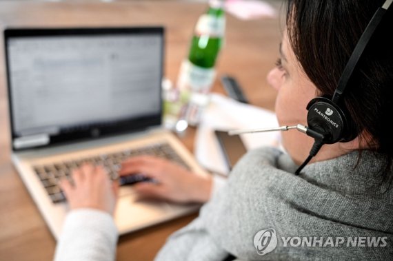 원격근무하는 여성. epa08933121 A woman with a headset sits in front of her laptop in the living room at home in Moenchengladbach, Germany, 12 January 2021. In view of the fact that the number of corona infections is not declining, politicians are calling for greater use to be made of working from home again