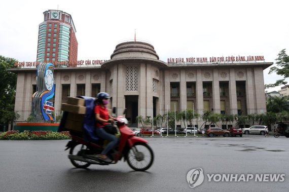 베트남 중앙은행(SBV) epa06082436 A woman rides a motorcycle past the State Bank of Vietnam (SBV) in central Hanoi, Vietnam, 12 July 2017. SBV announced it would cut a number of interest rates by 0.25-0.5 percent to stimulate growth and control inflation, starting from 10 July. EPA/LUONG THAI LINH